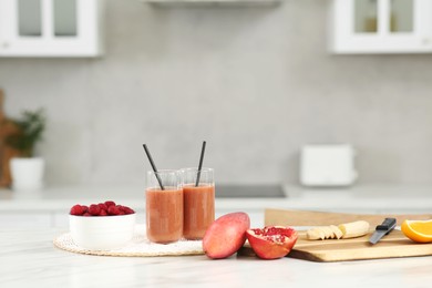 Photo of Tasty smoothie and ingredients on white marble table in kitchen