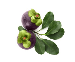 Delicious ripe mangosteens and green leaves on white background, top view