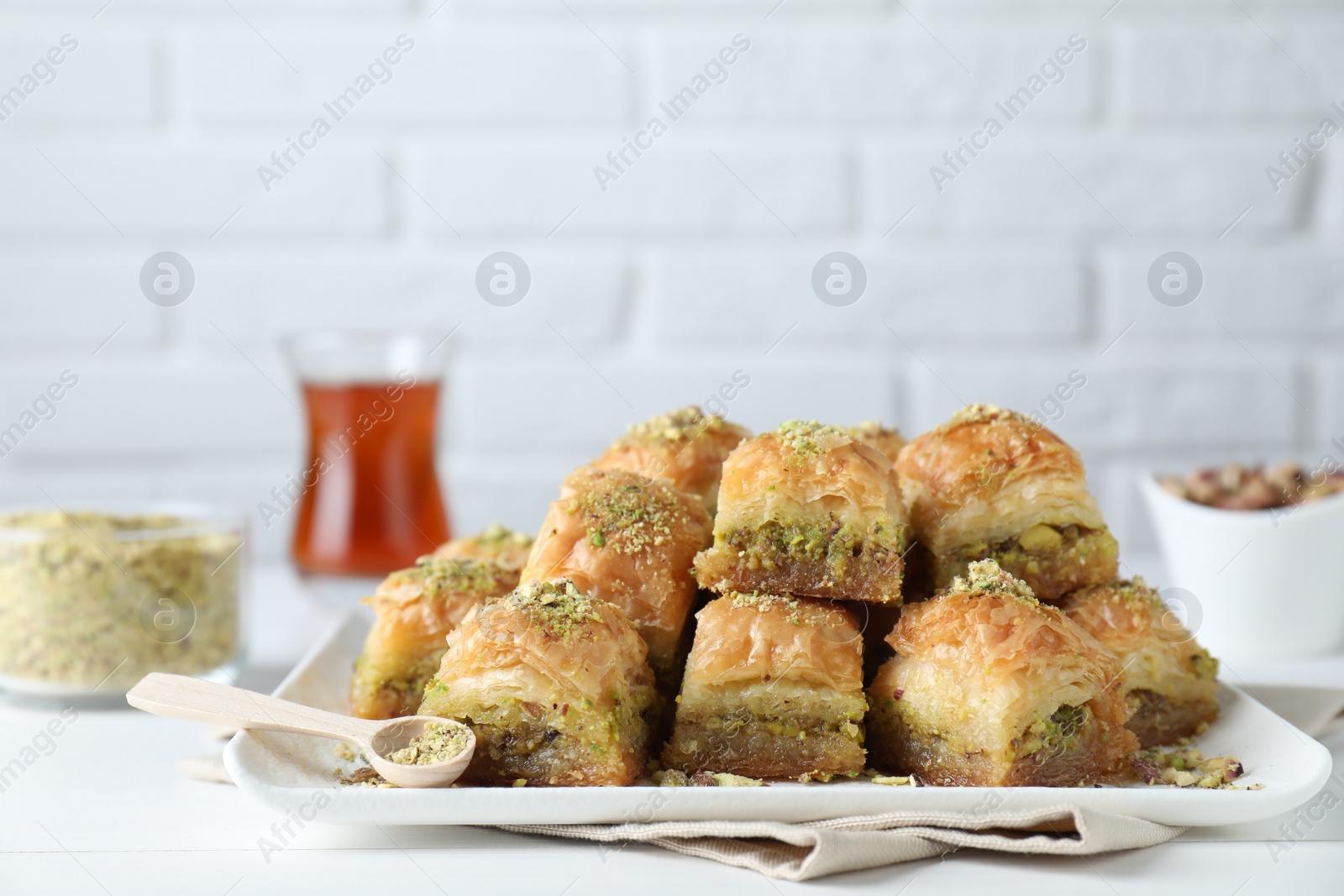 Photo of Delicious fresh baklava with chopped nuts on white table. Eastern sweets