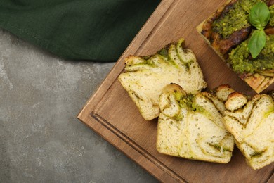 Freshly baked pesto bread with basil on grey table, flat lay. Space for text
