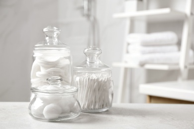 Photo of Cotton balls, swabs and pads on light grey table in bathroom