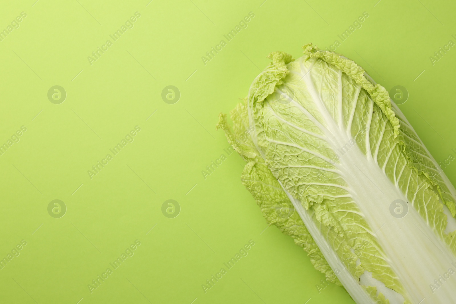 Photo of Fresh ripe Chinese cabbage on light green background, top view. Space for text