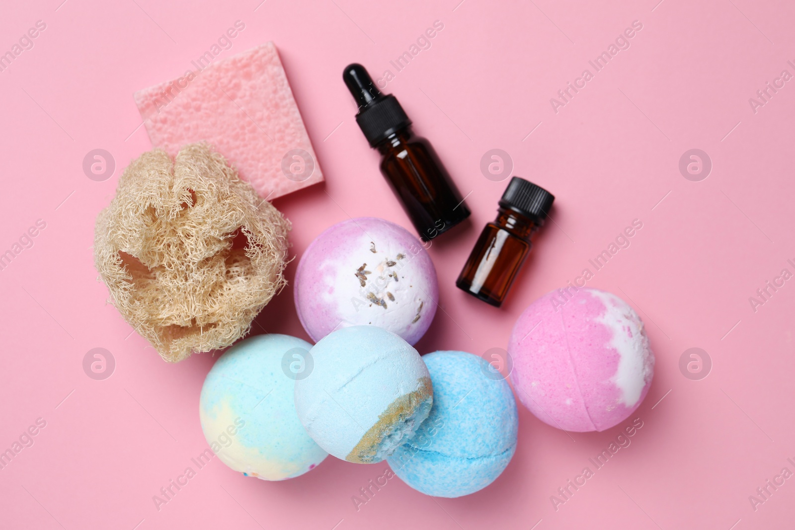Photo of Bath bombs, loofah sponge, soap bar and bottles on pink background, flat lay