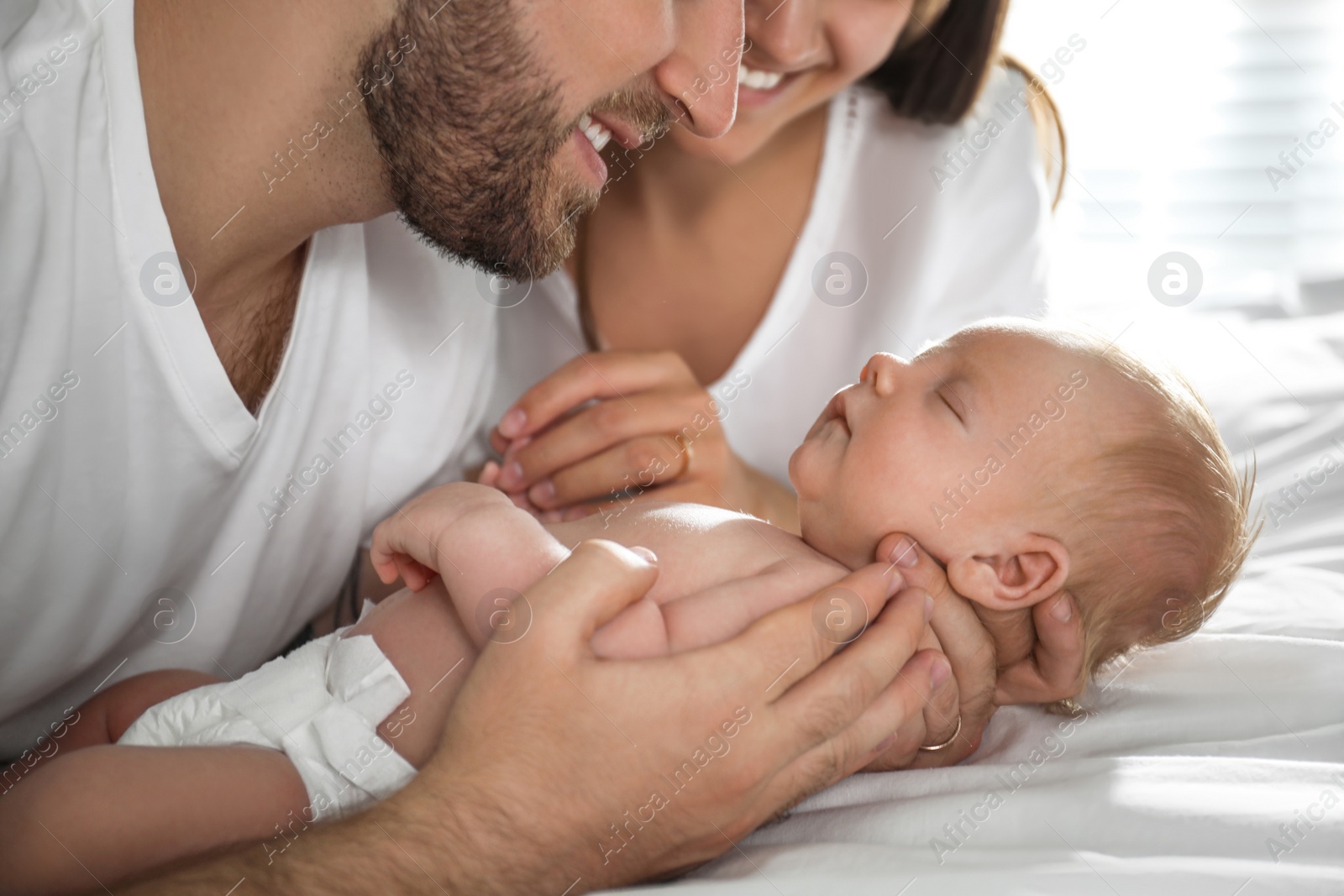 Photo of Happy couple with their newborn baby at home, closeup