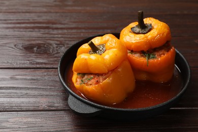 Photo of Tasty stuffed peppers in pan on wooden table, closeup. Space for text