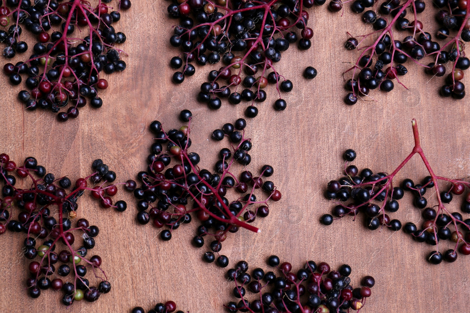 Photo of Tasty elderberries (Sambucus) on wooden table, flat lay