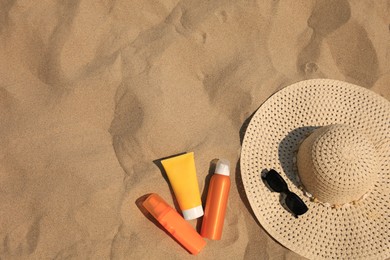 Flat lay composition with sunscreens on sand, space for text. Sun protection care