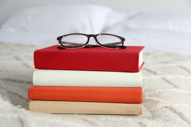 Photo of Books and glasses on white soft blanket in bedroom