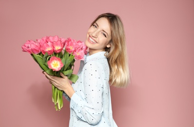 Photo of Portrait of beautiful smiling girl with spring tulips on pink background. International Women's Day