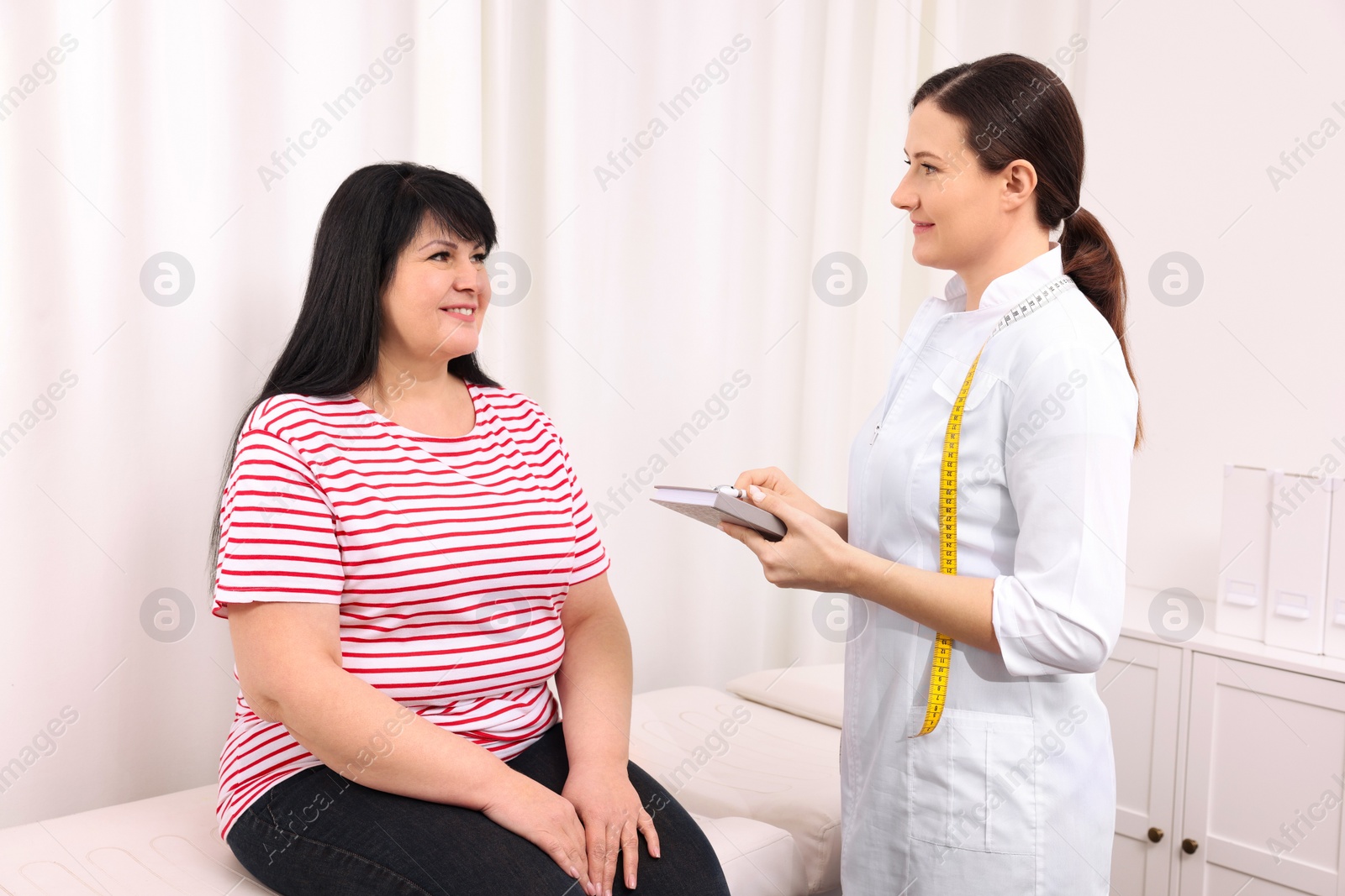 Photo of Overweight mature woman consulting with nutritionist in clinic