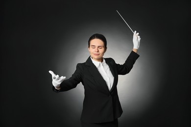 Professional conductor with baton on black background