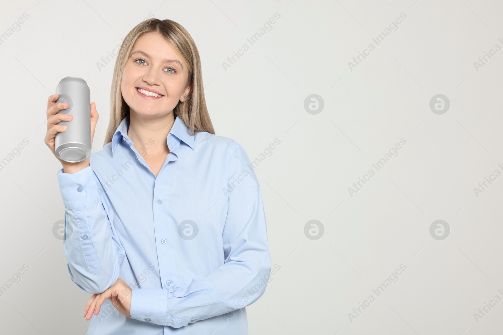 Photo of Beautiful happy woman holding beverage can on light background. Space for text