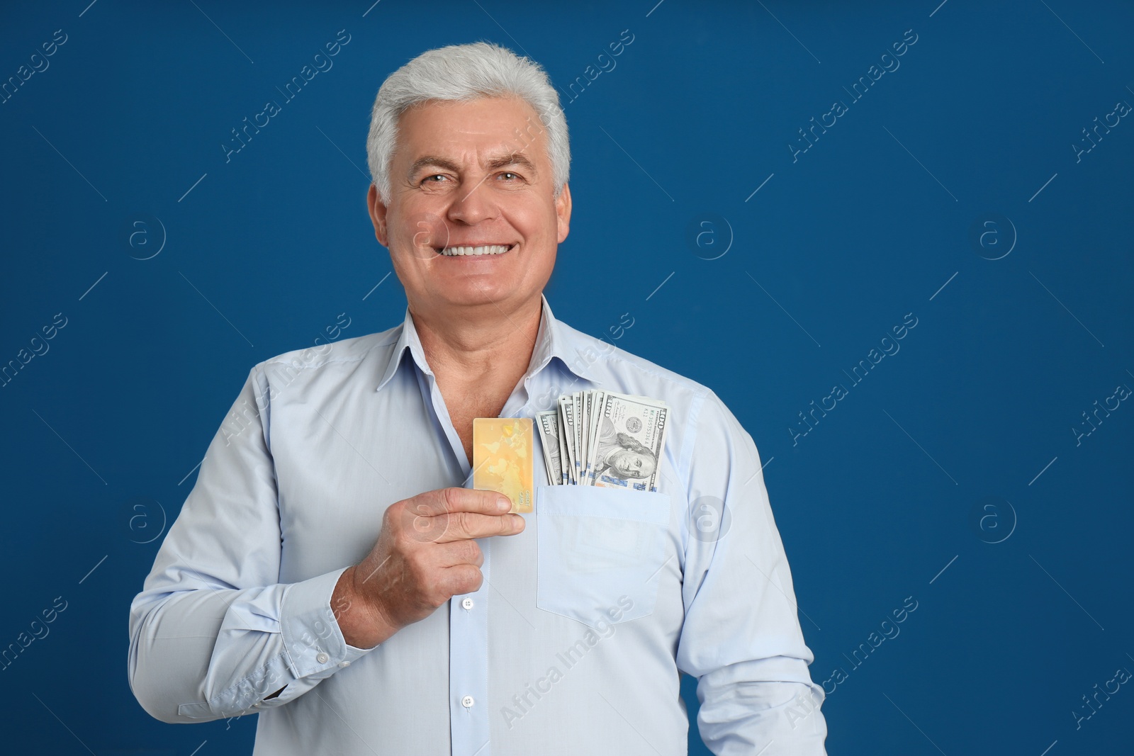 Photo of Happy senior man with cash money and credit card on blue background