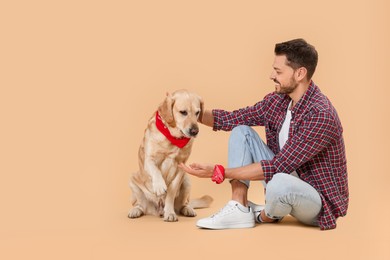 Photo of Cute Labrador Retriever giving paw to man on beige background