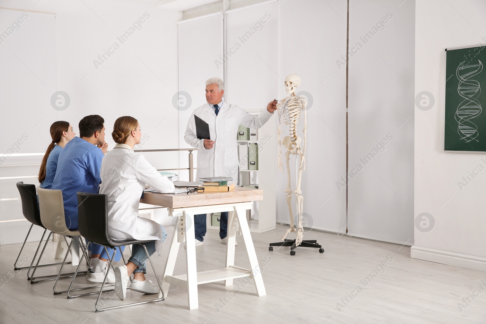 Photo of Medical students and professor studying human skeleton anatomy in classroom