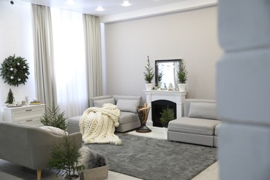 Photo of Stylish living room interior with little fir trees and Christmas decorations