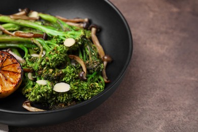 Photo of Tasty cooked broccolini with lemon and mushrooms on grey table, closeup. Space for text