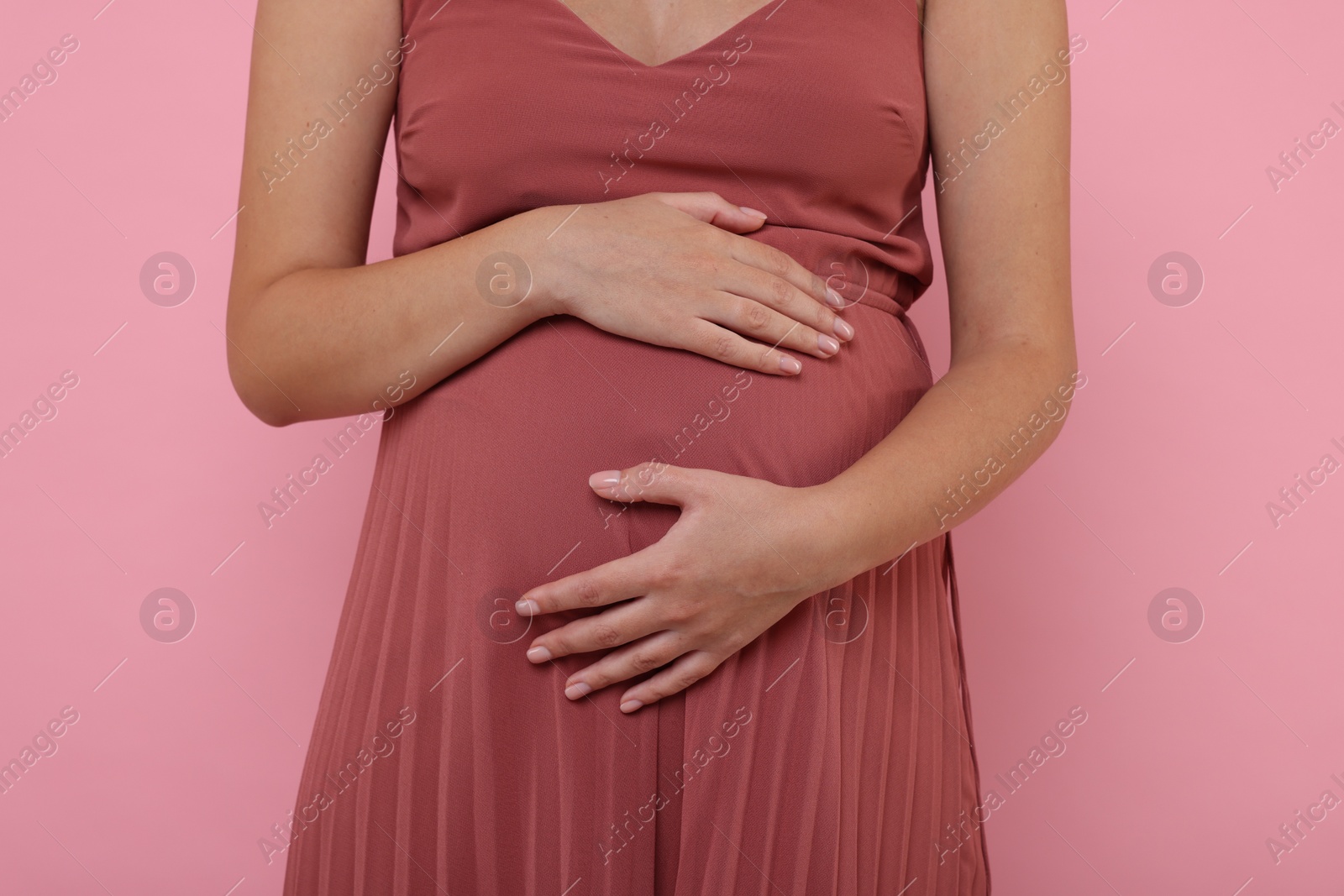 Photo of Pregnant woman in dress on pink background, closeup
