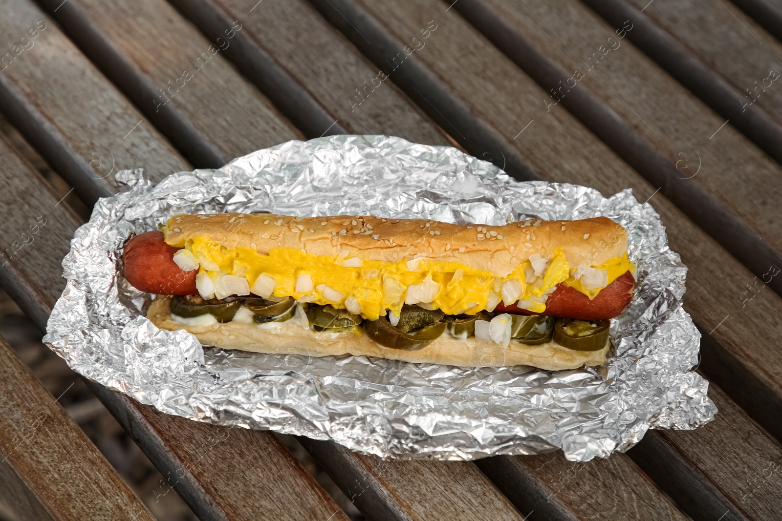 Photo of Fresh tasty hot dog with sauce on wooden surface