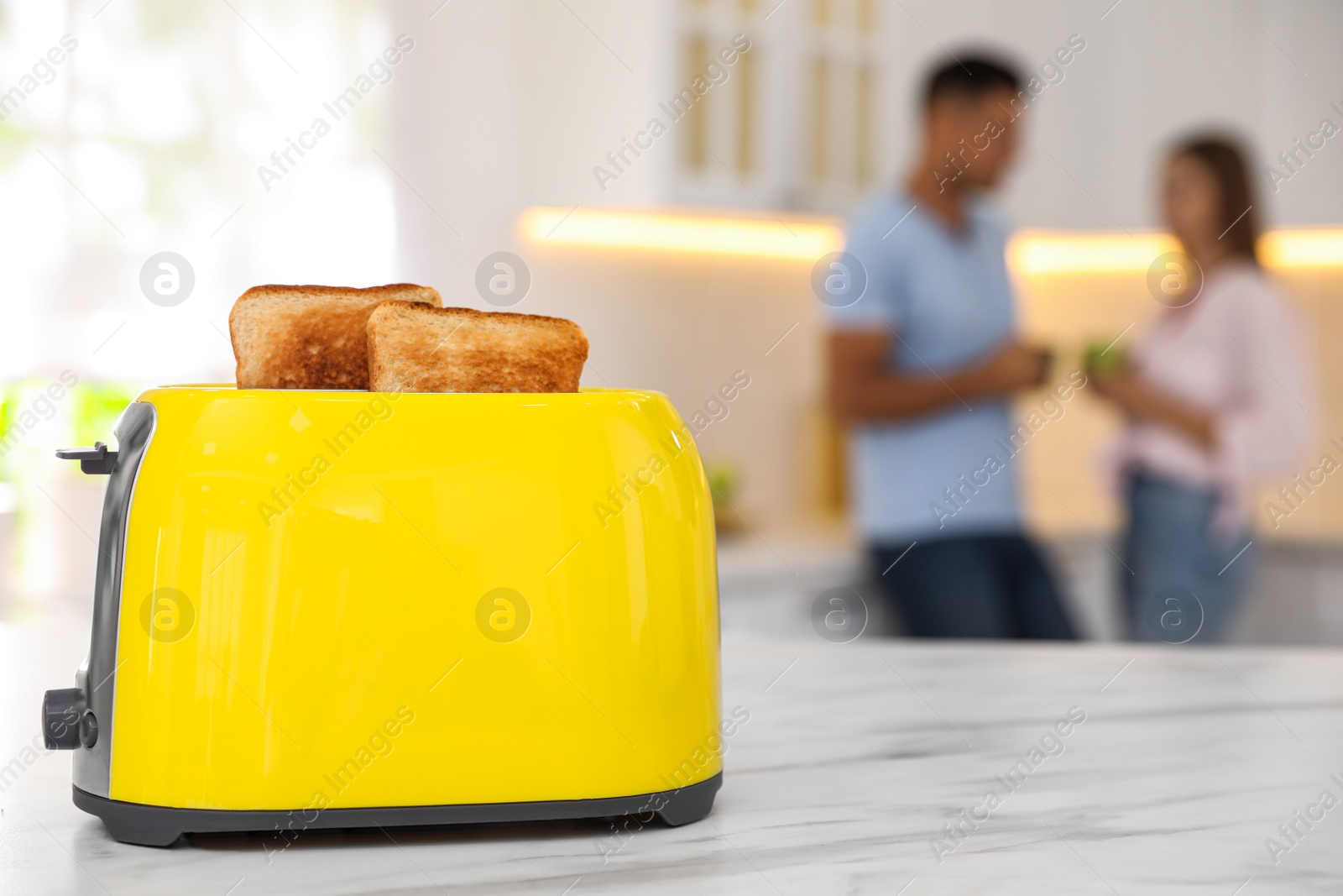 Photo of Modern toaster with slices of bread and blurred couple on background