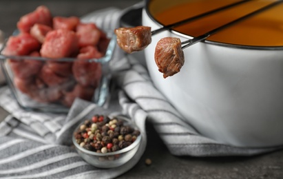 Photo of Fondue pot, meat and pepper on table, closeup