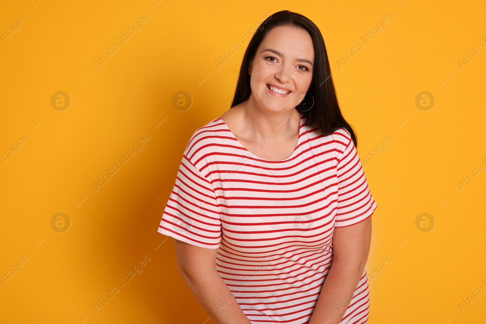 Photo of Beautiful overweight woman with charming smile on yellow background. Space for text