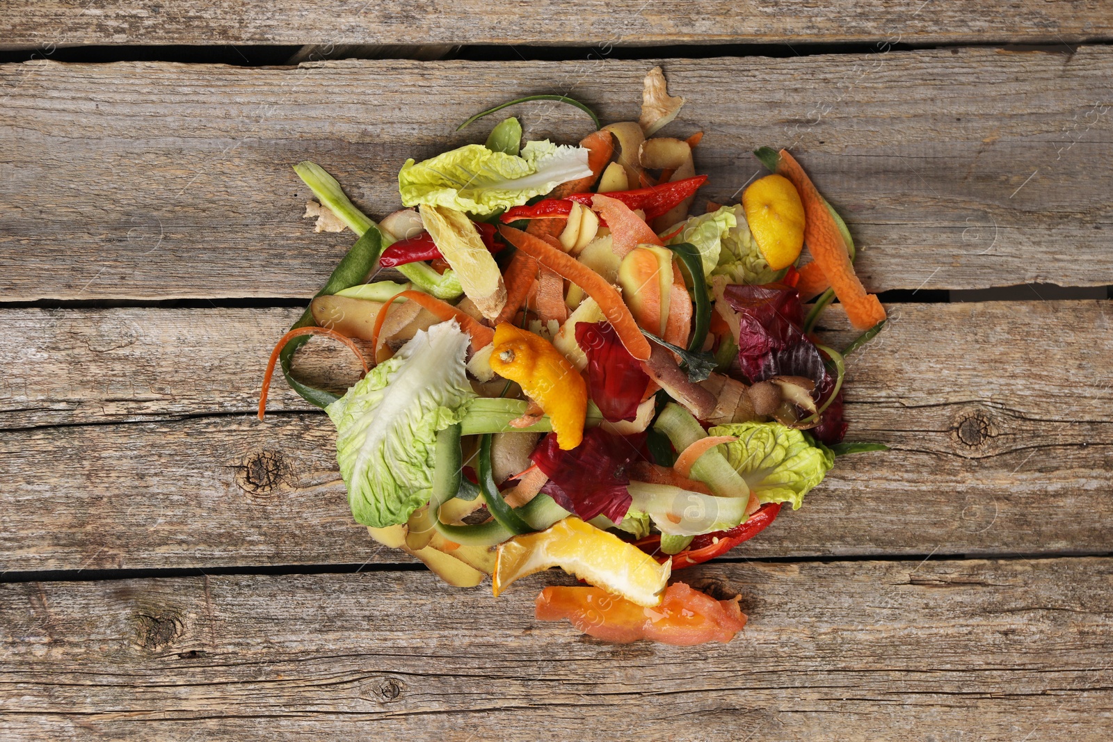 Photo of Peels of fresh vegetables on wooden table, top view