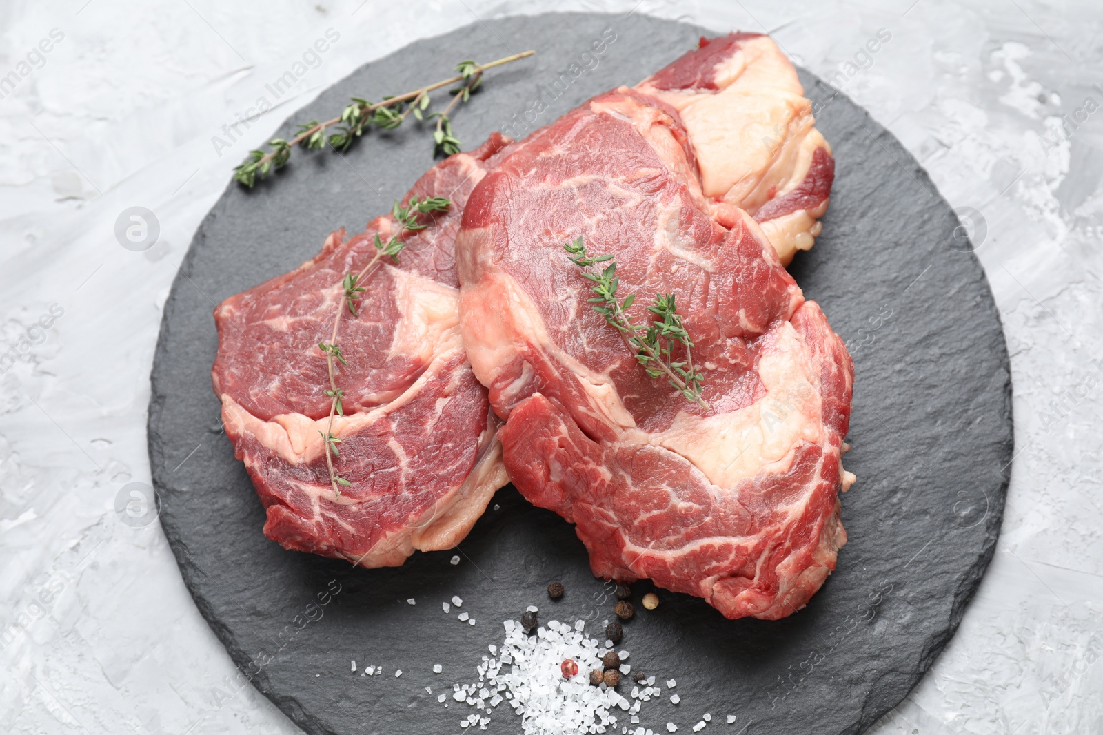 Photo of Fresh raw beef cut with different spices on light grey textured table, top view