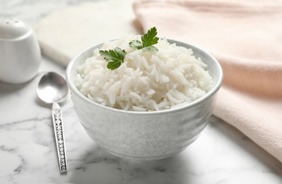 Photo of Bowl of tasty cooked rice with parsley served on table