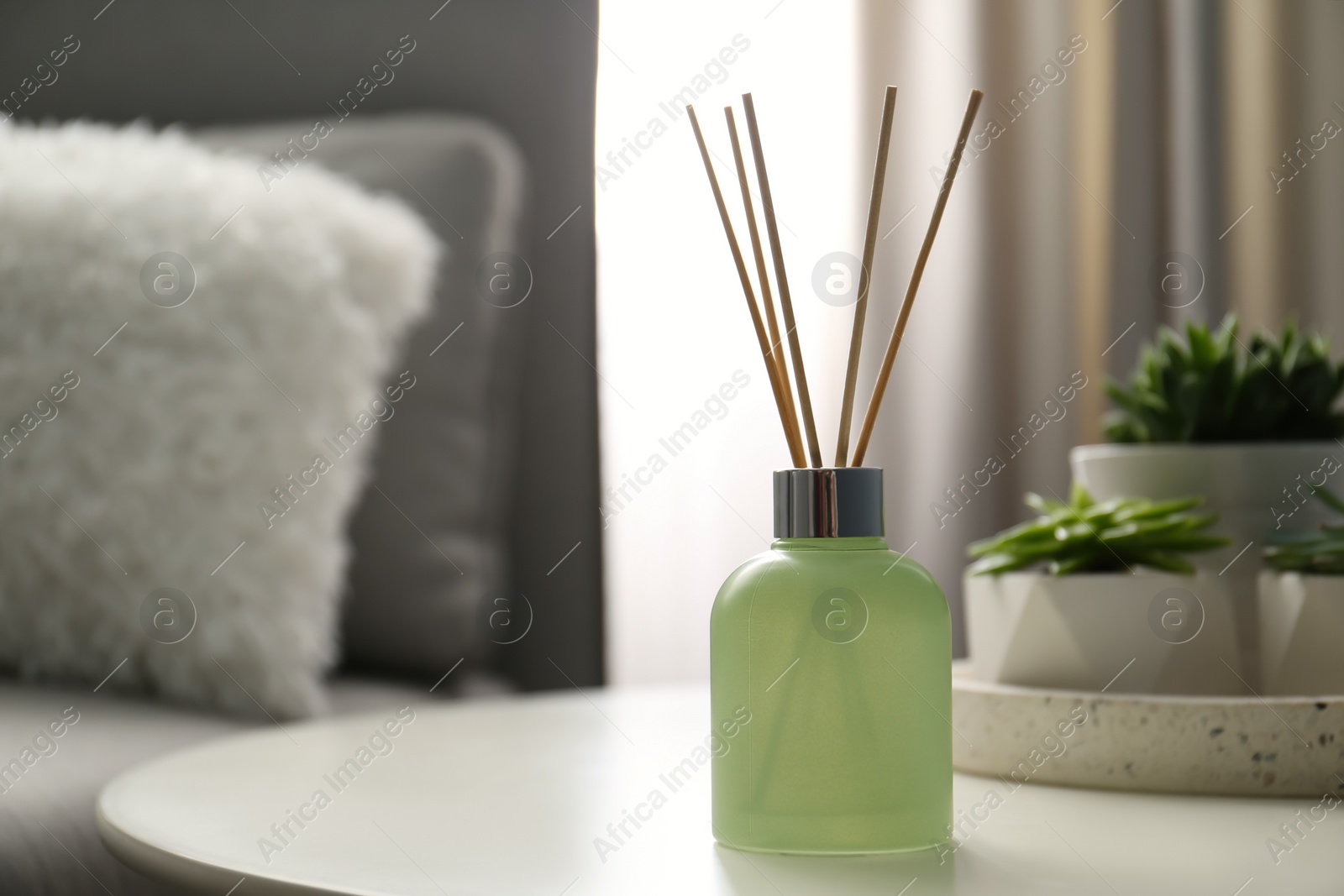 Photo of Aromatic reed air freshener on white table in room. Space for text