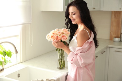 Photo of Young woman with beautiful bouquet in kitchen