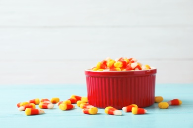 Photo of Bowl with delicious candies on table against wooden background