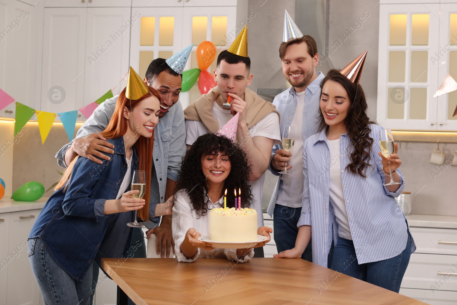 Photo of Happy friends with tasty cake celebrating birthday in kitchen