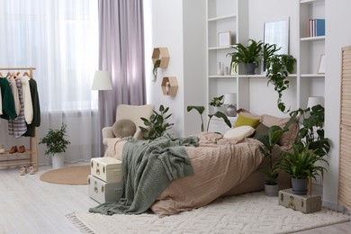 Stylish bedroom with comfortable bed and different houseplants. Interior design