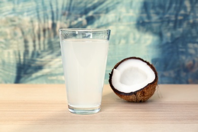 Photo of Glass with coconut water and fresh nut on wooden table