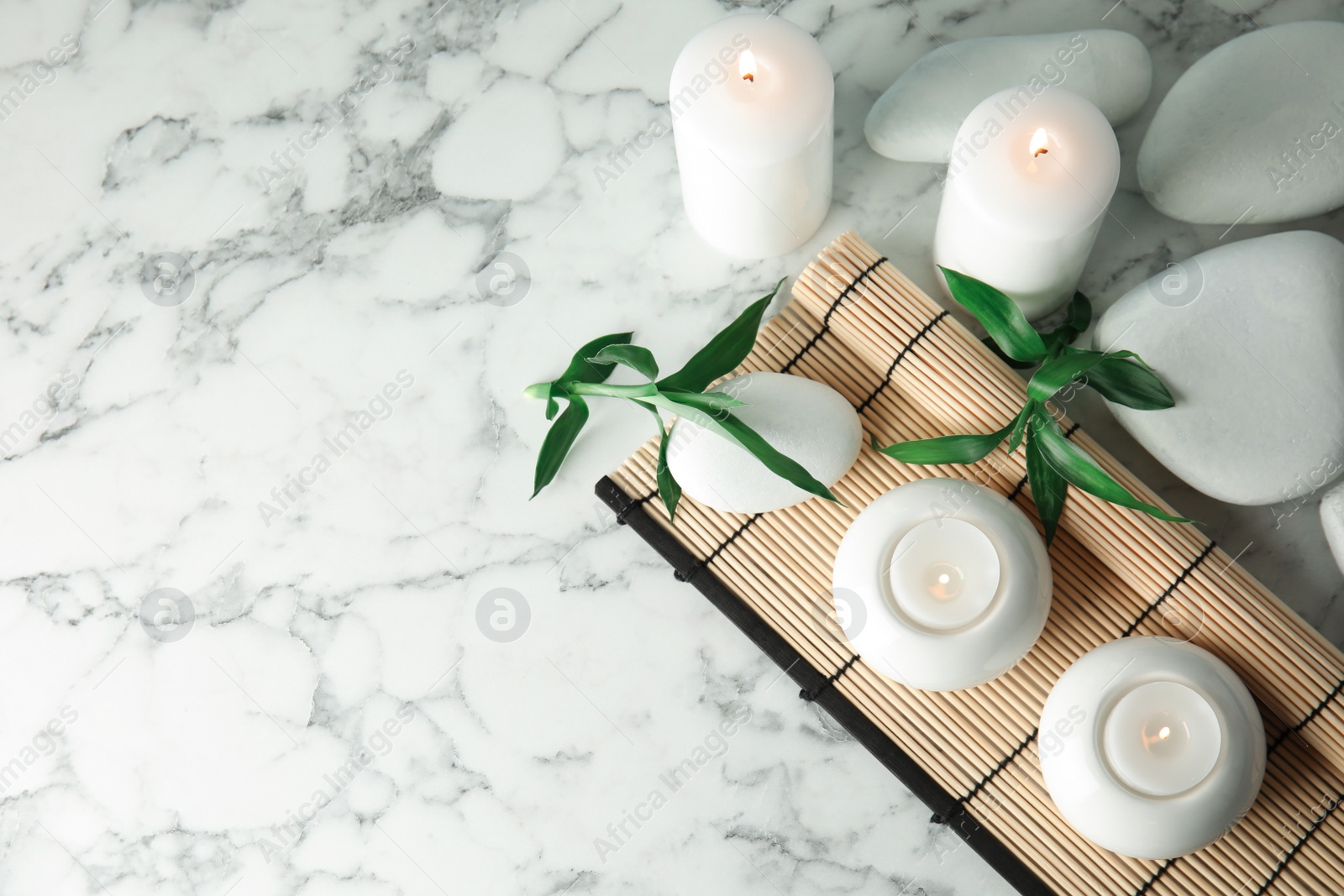 Photo of Beautiful spa composition with candles and bamboo mat on marble background, top view. Space for text