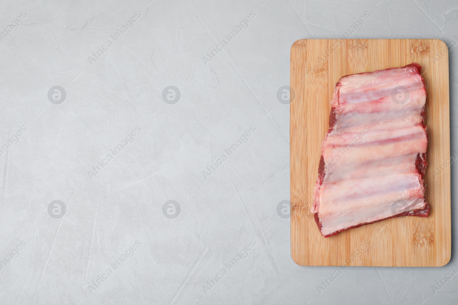 Photo of Board with raw ribs and space for text on grey background, top view. Fresh meat
