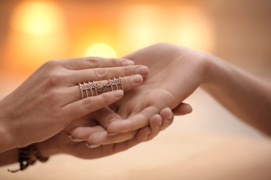 Photo of Chiromancer reading lines on woman's palm at table, closeup