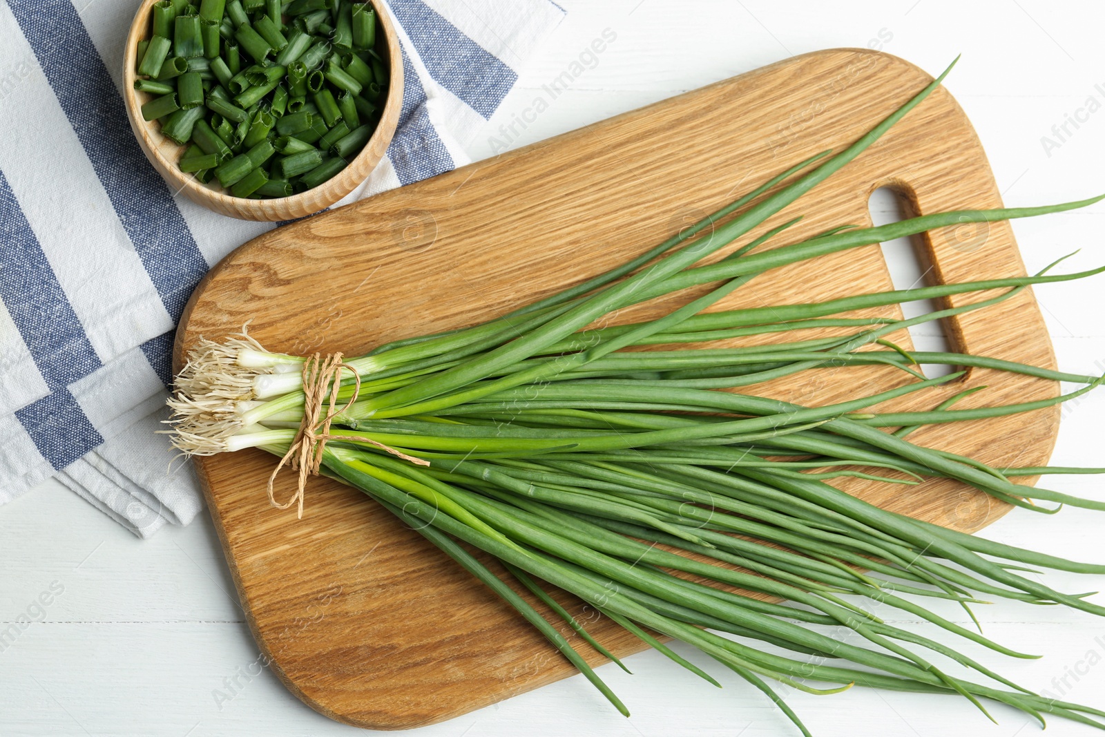 Photo of Fresh green spring onions on white wooden table, flat lay