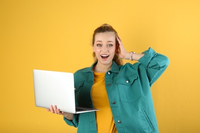 Photo of Portrait of emotional young woman with laptop on yellow background