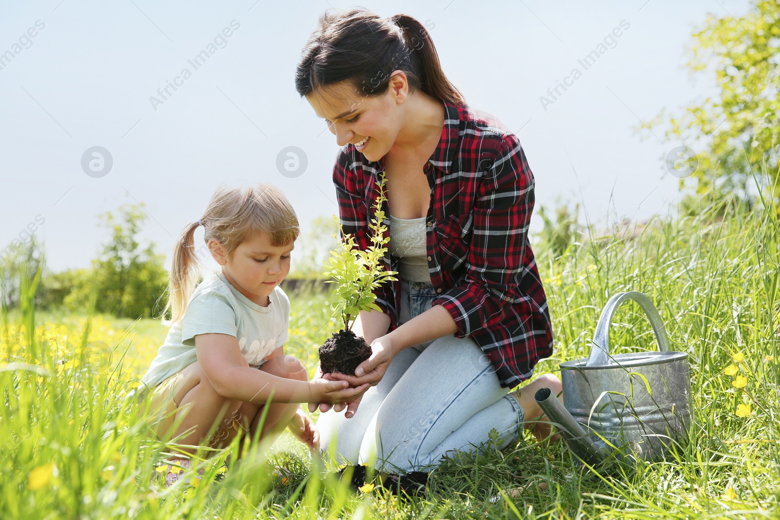 Photo of Mother and her daughter planting tree together outdoors