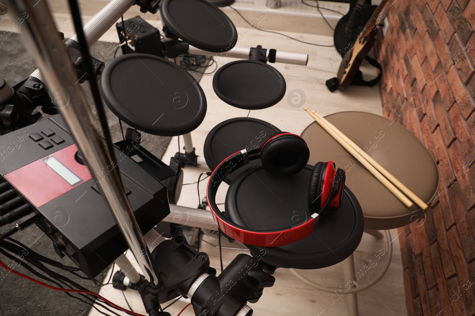 Photo of Modern electronic drum kit with headphones indoors, closeup. Musical instrument