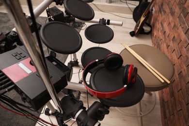 Modern electronic drum kit with headphones indoors, closeup. Musical instrument