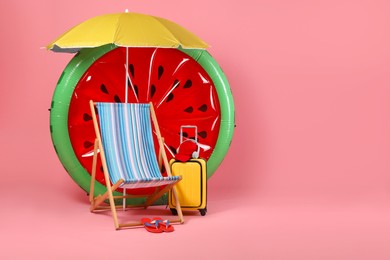 Deck chair, suitcase and beach accessories on pink background, space for text