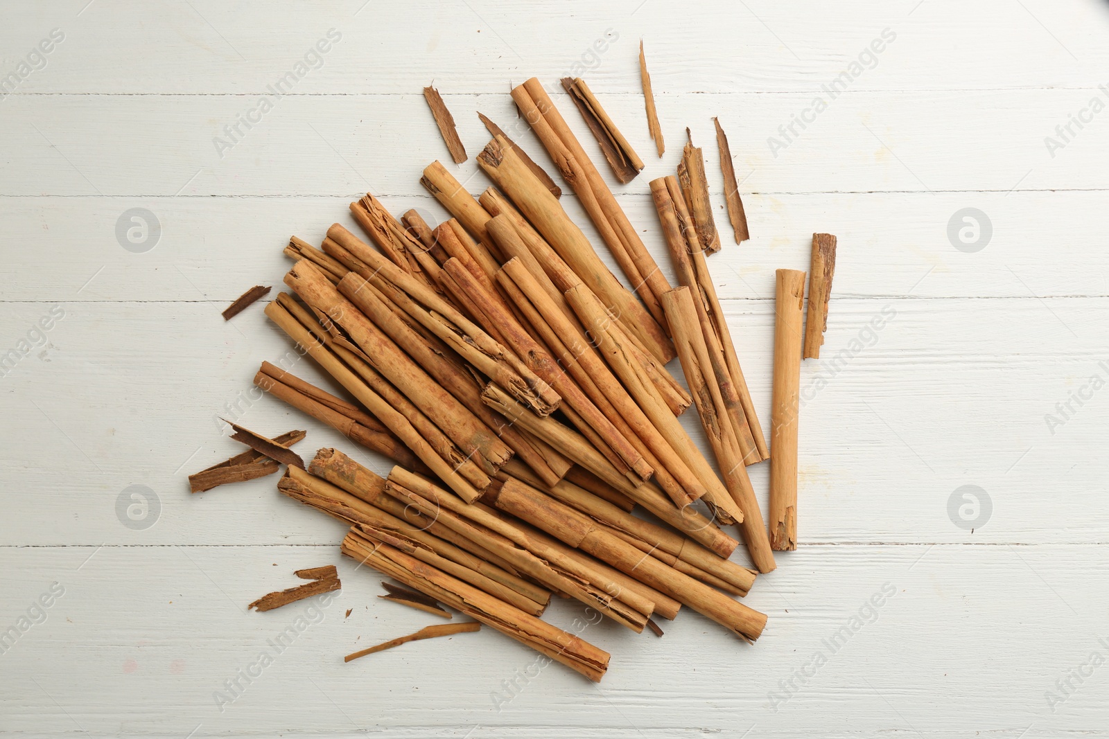 Photo of Aromatic cinnamon sticks on white wooden table, flat lay