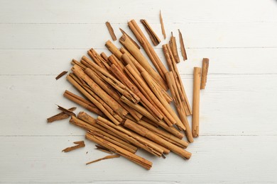 Aromatic cinnamon sticks on white wooden table, flat lay