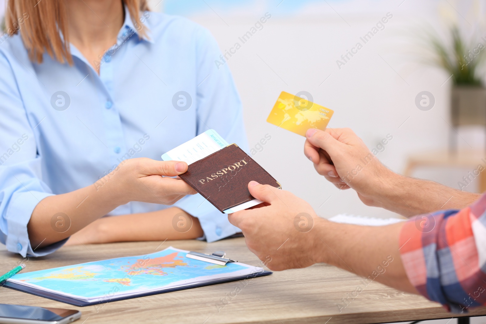 Photo of Female manager giving passport with ticket to client in travel agency