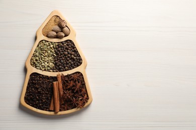 Photo of Different spices and nuts on white wooden table, top view. Space for text