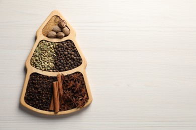 Different spices and nuts on white wooden table, top view. Space for text