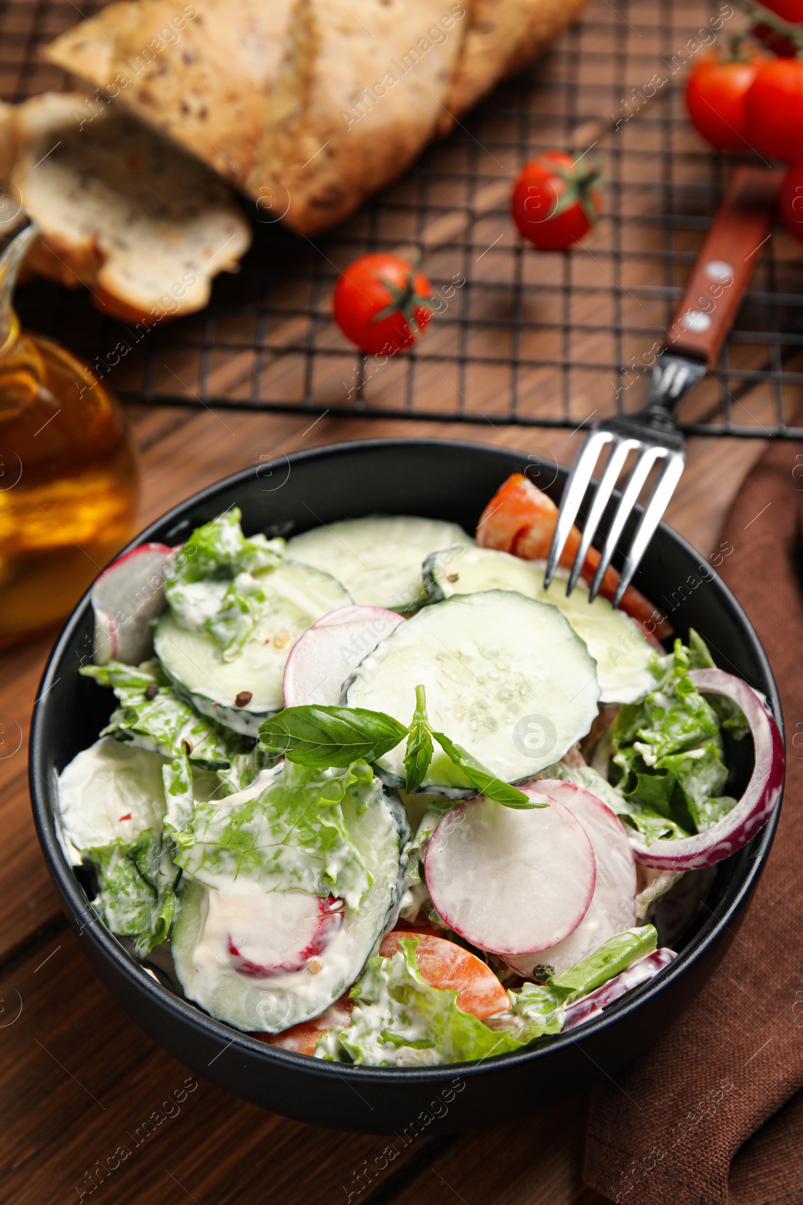 Photo of Bowl of delicious vegetable salad dressed with mayonnaise on wooden table